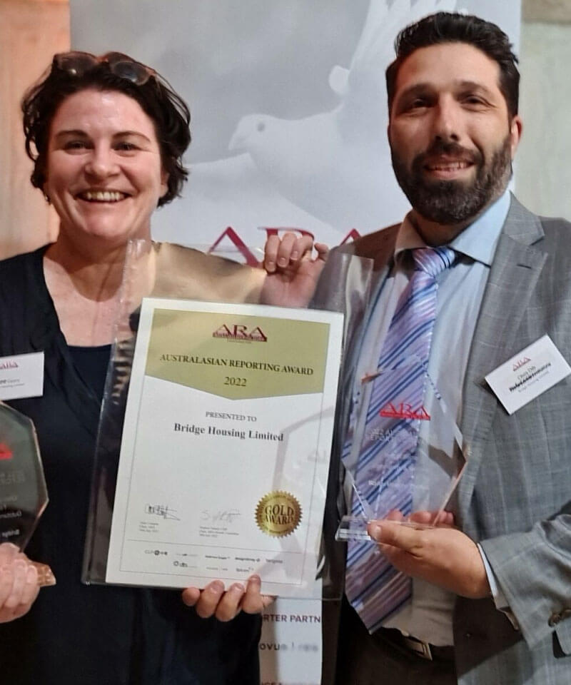 Two people proudly displaying Australasian Reporting Award 2022